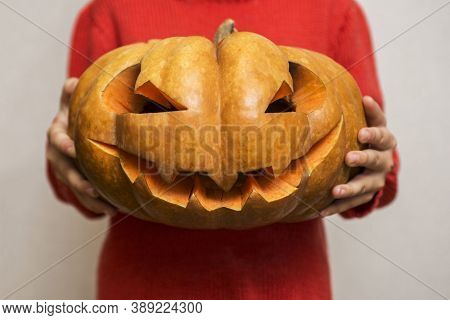 Halloween. Carved Orange Pumpkin On Kid Hands, Jack-o-lantern Traditional Symbol Of Halloween. Child