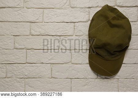 The Green Cap Hangs On The Light Colored Decorative Brick Wall On The Right Side