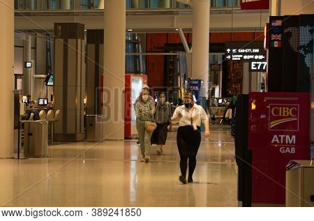 TORONTO, CANADA - 08 20 2020: Empty hall with few passengers wearing facial masks because of COVID-19 pandemic Canada health regulations and in night terminal at Toronto Pearson Intrnational airport