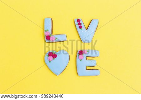Inscription Love By Homemade Cookies With Blue Icing On Yellow Pastel Color. Love Romance Concept. V