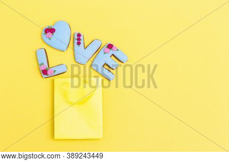 Inscription Love By Homemade Cookies With Blue Icing On Yellow Pastel Color. Cakes Escaped From Pape
