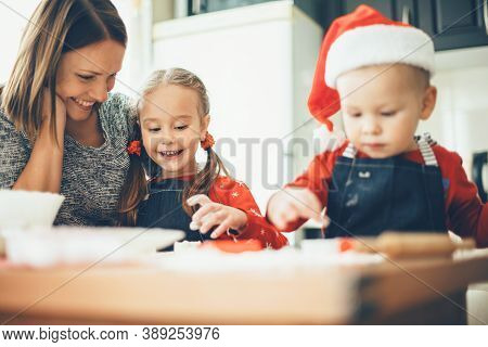 Caucasian Mother And Her Kids Preparing For Christmas Holidays Wearing Sant Clothes And Cooking Food