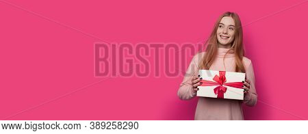 Ginger Woman With Freckles Is Advertising A Present Box On A Pink Wall With Free Space Smiling In Ca
