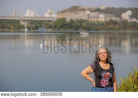 Closeup Of Smiling Mature Woman Wearing Glasses Standing On The Bank Of The Maas River With The Old 