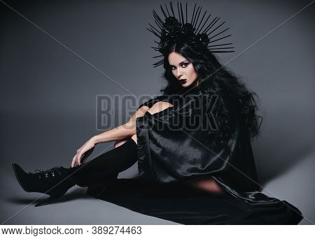 Halloween Theme: Beautiful Young Witch Dressed In Black Cloak And Headgear With Roses And Spikes. Da