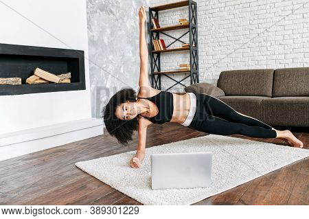 Fresh And Positive Attractive Female Millennial Is Watching Online Yoga Classes On The Laptop And Re