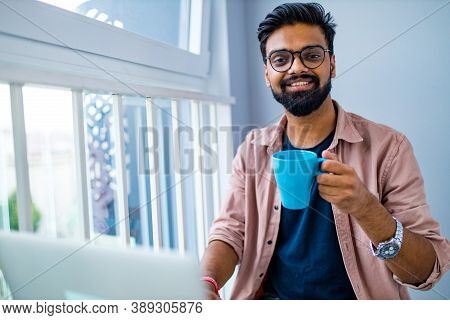 Arabian Man In Casual Dress Holning A Blue Cup And Looking Dreamly