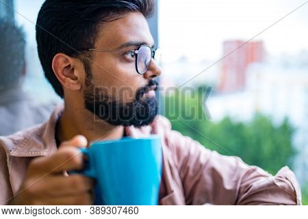 Arabian Man In Casual Dress Holning A Blue Cup And Looking Dreamly