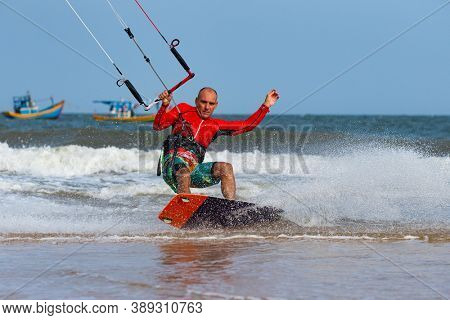 Kitesurfing on the waves of the sea in Mui Ne beach, Phan Thiet, Binh Thuan, Vietnam. Kitesurfing, Kiteboarding action photos. Kitesurf In Action 