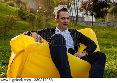 Feel Free. Handsome Young Man Lying On Inflatable Sofa Lamzac While Resting In Park.