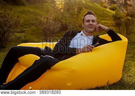 Feel Free. Handsome Young Man Lying On Inflatable Sofa Lamzac While Resting In Park.