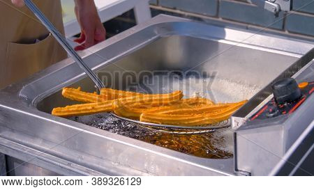 Chef Cooking Homemade Crunchy Yellow Churros In Boiling Oil At Summer Outdoor Food Market - Close Up