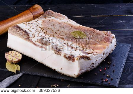Chunks Of Salted Bacon On Dark Background. Healthy Food With Pranami And Herbs. Salted Fat, Lard, Ta