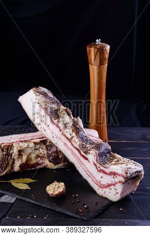 Chunks Of Salted Bacon On Dark Background. Healthy Food With Pranami And Herbs. Salted Fat, Lard, Ta