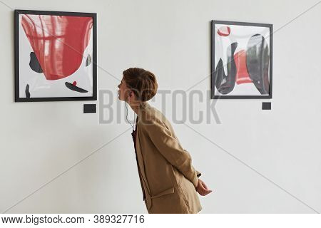 Wide Angle Portrait Of Tattooed Young Woman Looking At Paintings And Listening To Audio Guide At Mod