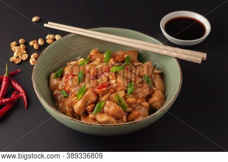 Kung Bao Chicken On A Black Background. A Chinese Dish With Chicken, Chili, Peanuts, Sauces And Onio