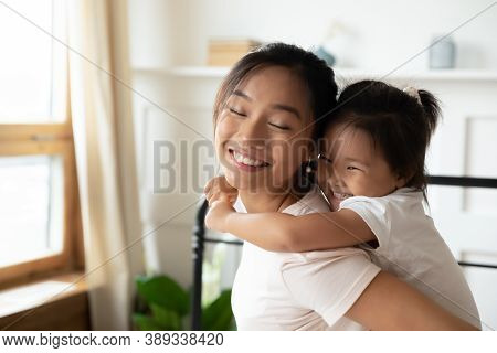 Close Up Smiling Asian Mother Piggy Backing Little Daughter