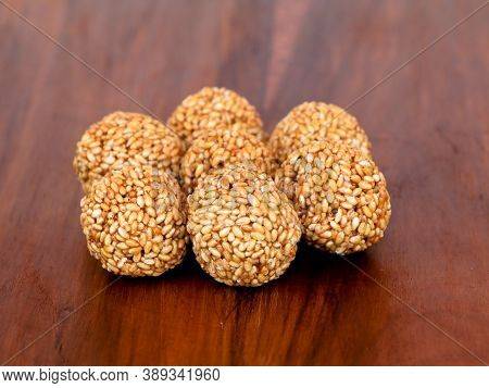 White Sesame Seed Balls Made With Heated Jiggery Against Wooden Background