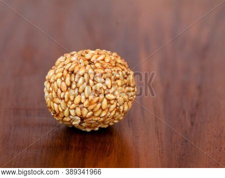 White Sesame Seed Balls Made With Heated Jiggery Against Wooden Background