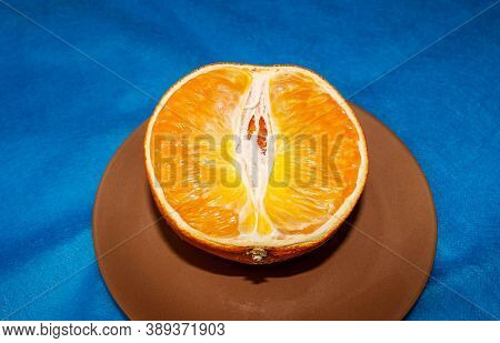 Half-dried Half Of An Orange That Lies On A Saucer On A Blue Background. Selective Shot.