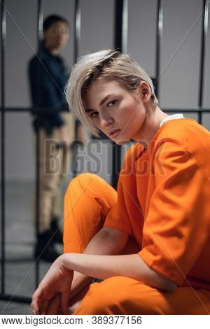 A Beautiful Young Girl Is Placed Under Arrest In An Asian Prison. Sitting In A Cell. In The Backgrou