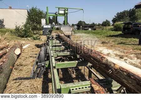 Mobile Sawing Equipment For Logs In The Open Air. Rural Landscape On A Sunny Day. Mobility And Work 