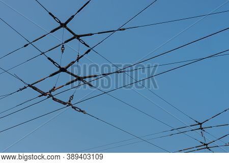 On The Background Of A Clear Blue Sky, The Intersection Of Tram Wires. Transport Electric Wires For 