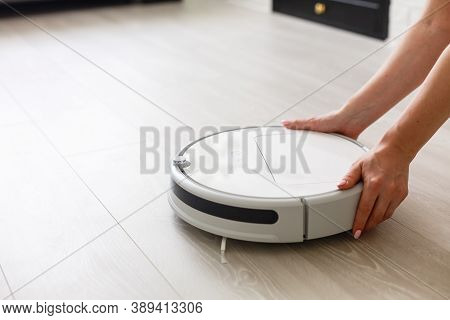White Robot Vacuum Cleaner Cleans The Floor From Debris, Home Cleaning With An Electric Vacuum Clean