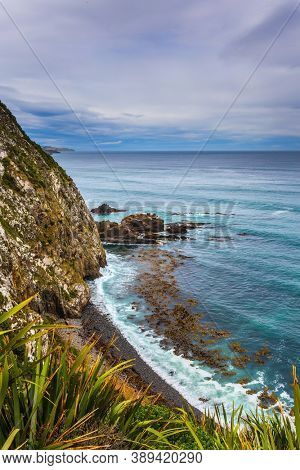  Sunset portends a storm. South Island, New Zealand. The picturesque coast of the Pacific Ocean near Cape Nugget. The concept of active, environmental and photo tourism