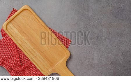 Wooden Bread Cutting Board Blank And Red Napkin On Polished Cement Background. Top View.