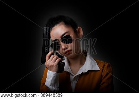 Portrait Beautiful Asia Woman Wearing A Yellow Suit One Hand Holding A Pistol Gun At The Black Backg