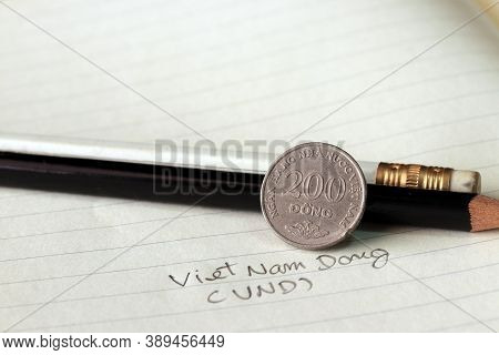 Two Hundred Vietnam Dong Coin On Reverse (vnd) With Black And White Pencil On The Book.