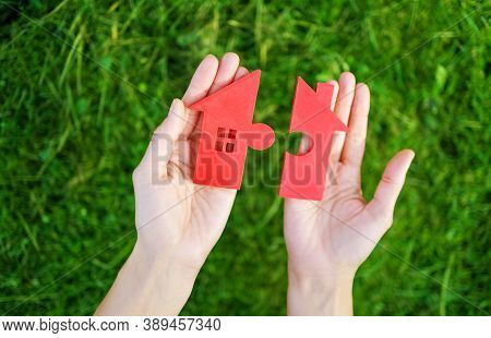 Red House With A Shape Of Two Parts Of Puzzle In Human Hands