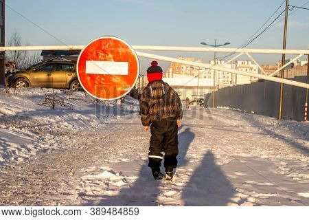 The Boy Stands In The Winter On The Road In Front Of The Sign Travel Is Prohibited. The Boy Is Afrai