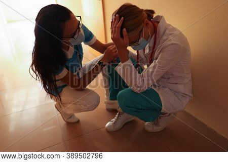 Nurse Calms Crying Doctor Wearing Medical Protective Mask In Bright Hospital Corridor. Psychological