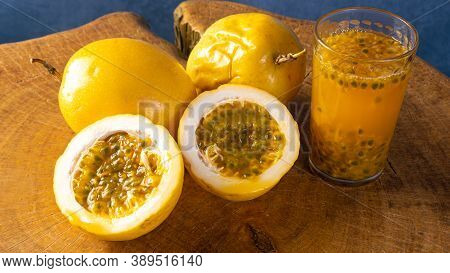 Passion Fruit And A Glass Of Juice On Rustic Wood, Blue Background, Selective Focus.