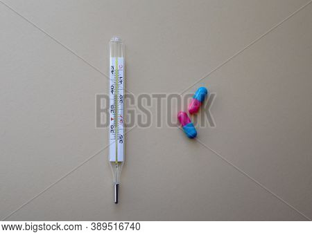 Thermometer And Pills On Neutral Background. First Aid, Care During Illness. Horizontal