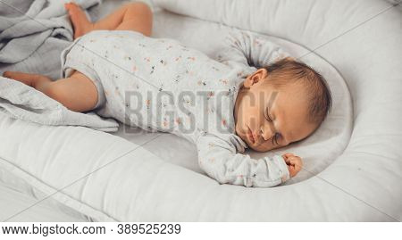 Newborn Baby Sleeping In Safe In Her Bed On A White Blanket At Home