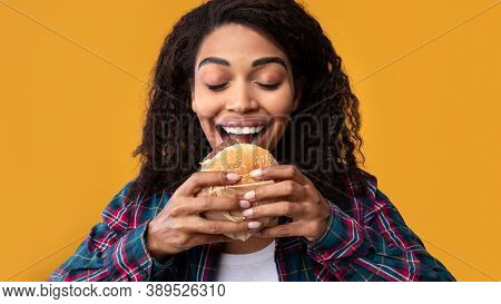 Junk Food. Closeup Portrait Of Hungry African American Woman Eating Tasty Burger. Funny Woman Holdin
