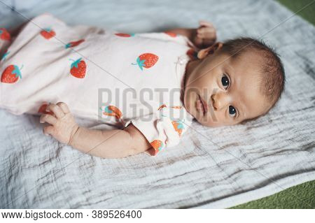 Newborn Baby Looking At Camera Wearing Nice Clothes While Lying On A Blanket At Home