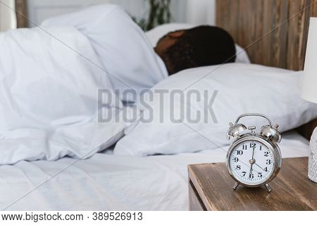Oversleeping. Overslept Black Man Sleeping Through Alarm Clock In The Morning Lying In Bed At Home, 