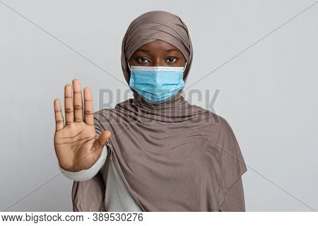 Stop Coronavirus Pandemic. Portrait Of Black Muslim Woman Wearing Medical Protective Mask And Hijab 