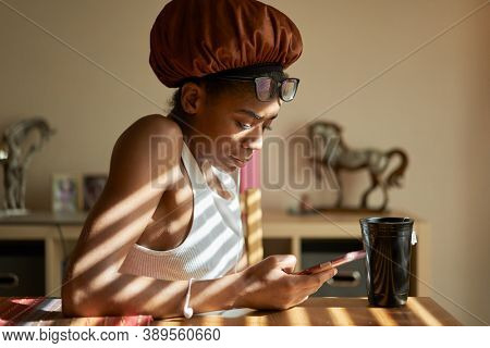 african american woman wearing showercap looking at smartphone during morning routine