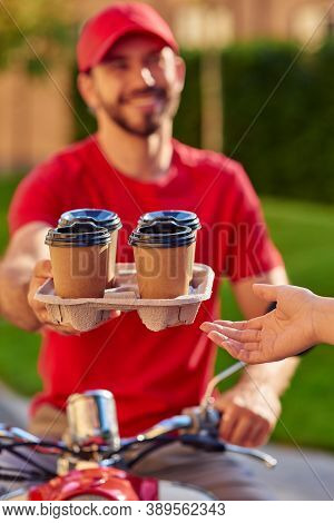 Smiling Courier Giving Coffee Cups To Customer