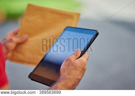 Digital Tablet And Paper Packet In Hands