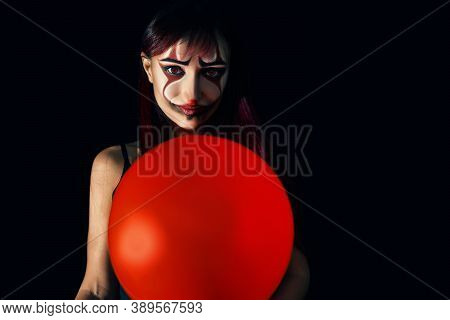 Close Up Portrait Of A Redhead Girl With Evil Clown Makeup, Background Is Black.