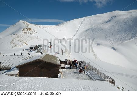 Les Orres, France - Circa 2015: Ski lift to the top of the slopes and restaurant clearing off fresh snow from the balcony to reopen it