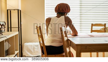 african american woman wearing showercap looking at smartphone during morning routine