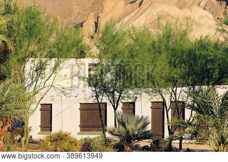 Spanish Style Hacienda Villa Surrounded By Arid Drought Tolerant Plants And Palm Trees Besides Barre