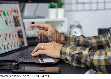 Asian Man Holding Credit Card To Online Shopping With Laptop Computer And Entering Security Code, In